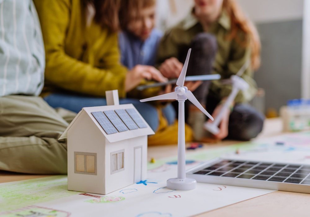 Close-up of a house model with solar system and wind turbine during a school lesson.